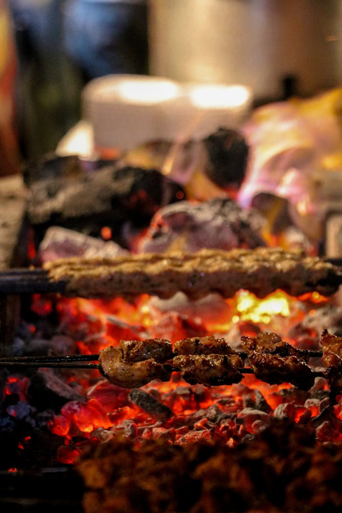 Services Close-up of assorted meats grilling over glowing charcoal, showcasing smoke and intense heat.