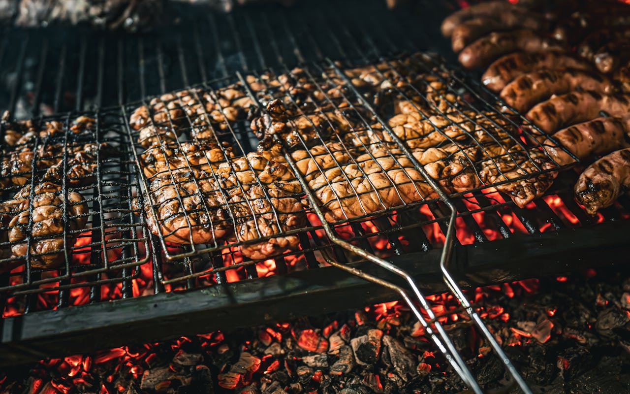 Services Grilled meat and sausages sizzling on a barbecue over hot coals, capturing the essence of outdoor cooking in Argentina.